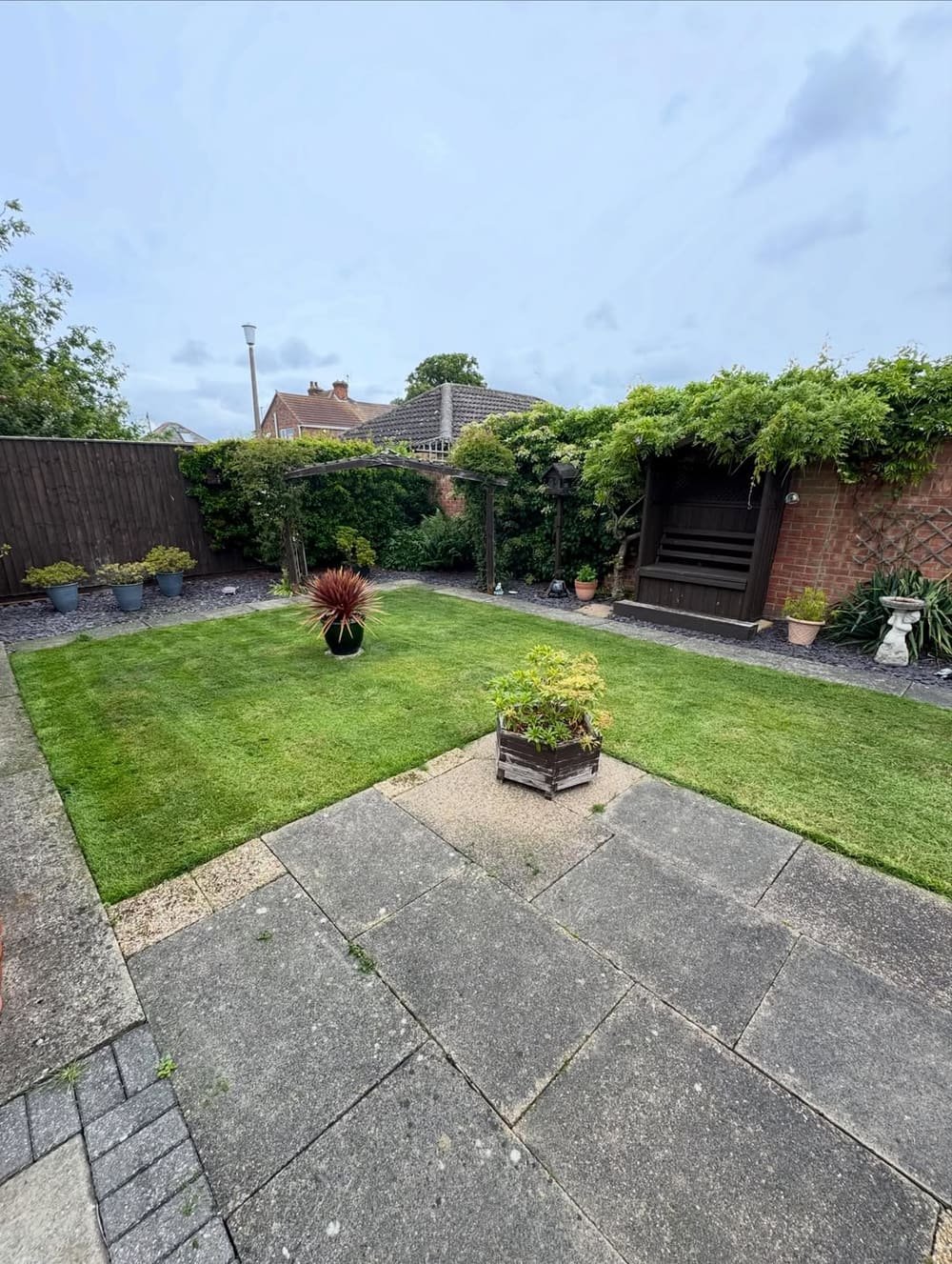 A neatly maintained back garden with a mowed lawn, tidy borders and patio, cared for by Carratt's Garden Maintenance
